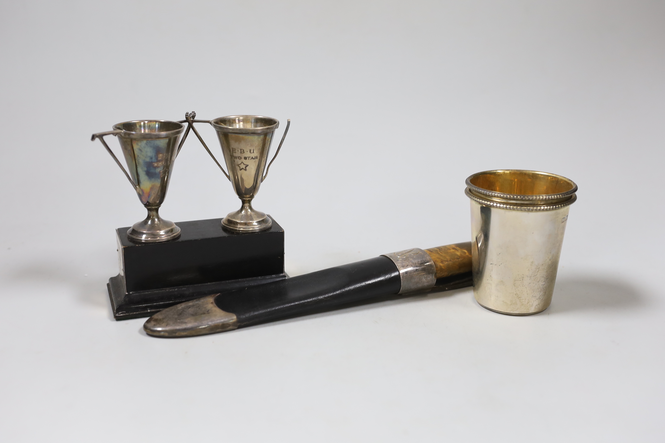 A pair of small silver beakers with gilt interiors and leaded rims, WW, London, 2000, 70mm, two small trophy cups on plinth and a knife in leather scabbard., NB: From the Estate of Rt Hon Lord Lawson of Blaby